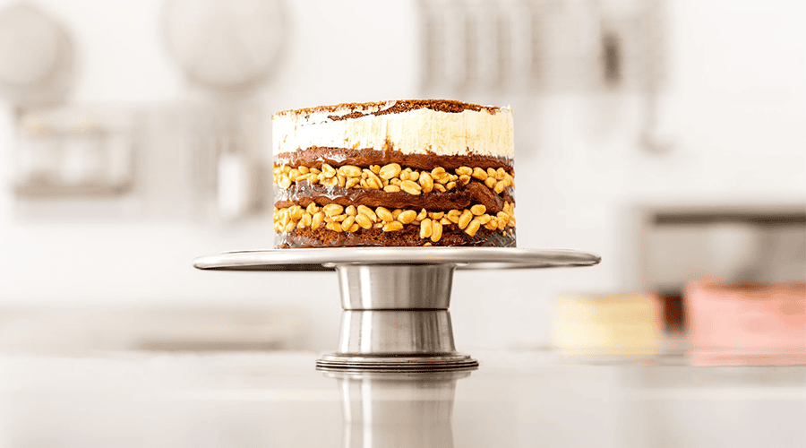 Leckere Schichttorte mit Nüssen und Creme auf Kuchenständer.