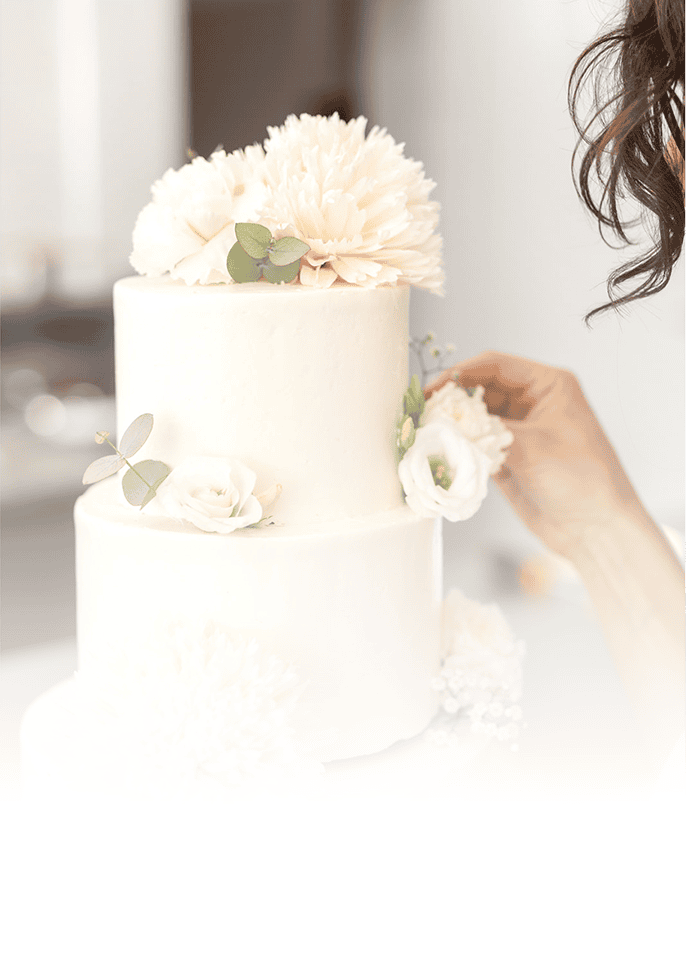 Elegante weiße Hochzeitstorte mit Blumen und Eukalyptus.