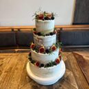 Mehrstöckige Hochzeitstorte mit Beeren und Kräutern.